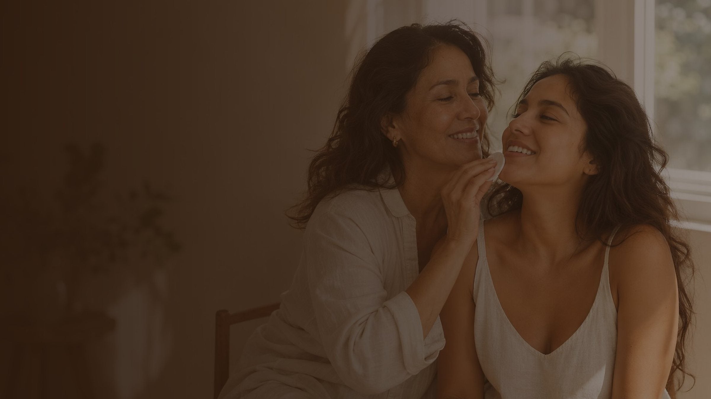 Dos mujeres riéndose juntas en una habitación con luz cálida